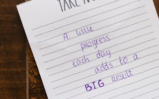 Motivational note on paper with handwritten text on a wooden table.