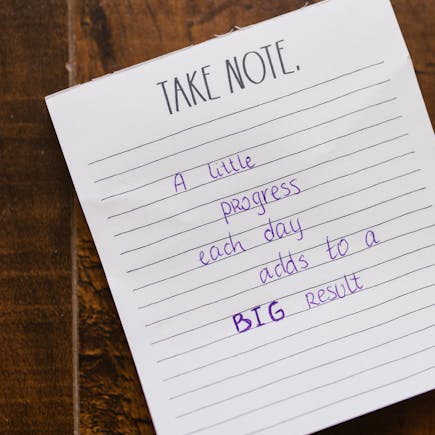 Motivational note on paper with handwritten text on a wooden table.