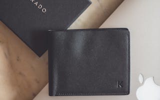 Stylish flat lay showcasing a black leather wallet and modern technology devices on a marble surface.