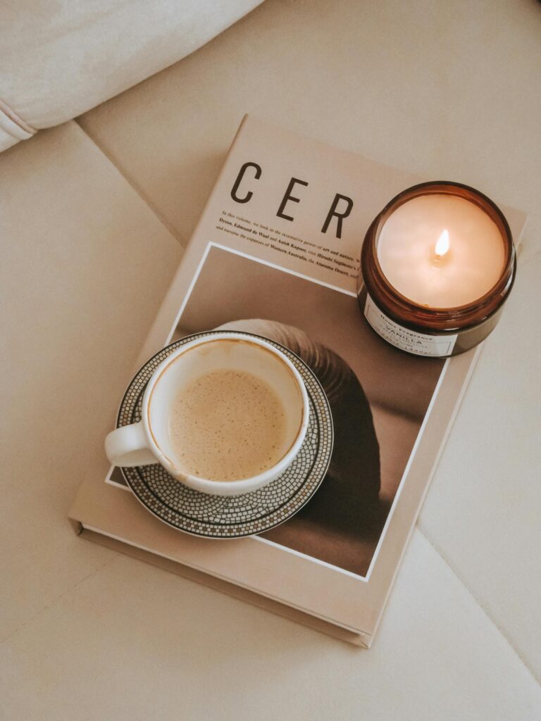 Warm and inviting flat lay with coffee, candle, and magazine showcasing hygge lifestyle.